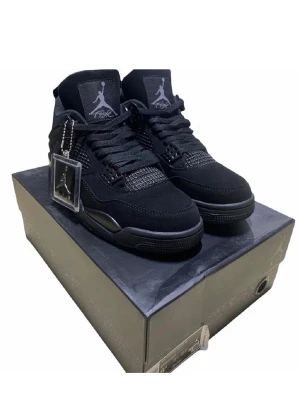 Svarta Air Jordan 4 Retro sneakers - Snygga helsvarta Air Jordan 4 Retro sneakers med ikoniska Jumpman-loggan på plösen. Skorna har meshdetaljer, mockaliknande material och plastdetaljer vid snörningen. Klassisk siluett med hög komfort och cool streetwear-vibe.