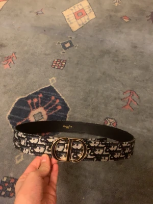 Svart och vit bälte med kattmönster - Unikt bälte med svart och vit färg och ett coolt kattmönster längs hela bandet. Perfekt för att ge din outfit en personlig touch. Bältet är smalt och har en klassisk form, passar till jeans eller kjol.