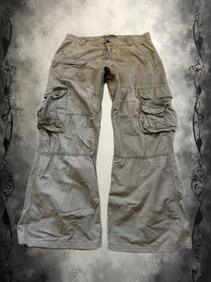 Beiga vida cargobyxor med fickor - Säljer ett par beiga cargobyxor med bred passform och flera stora fickor på sidorna. Byxorna har klassisk cargostil med knapp och dragkedja framtill. Perfekta för en avslappnad streetwear-look.
