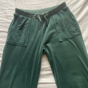 Juicy Couture - Mörkgröna mjukisbyxor från Juicy Couture med snörning i midjan och stora fickor fram. Bakficka med knappdetaljer och broderad logga på ena fickan. De är i storlek 12-13 år men passar xs.💕