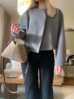 Snygg grå bort jacka  - Snygg grå kort jacka i stilren och minimalistisk design. Perfekt till både vardag och mer uppklädda outfits. Den har en modern, något oversized passform utan knappar framtill vilket ger en väldigt elegant look🤍 Storlek M