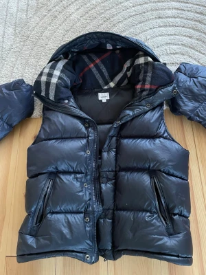 Burburry väst/jacka (äkta!) - Snygg mörkblå dunväst från Burberry med avtagbara ärmar. De tråkiga är att de finns lite slitningar på ryggen men inget hål utan bara typ som rivmärken, sen är de att en dragkedja alltså en av dom på magen inte går att stänga tyvärr men annars är det en fin jacka/väst. 