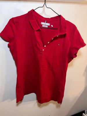  pikétröja från M/L(XL) - Klassisk röd pikétröja från Tommy Hilfiger med korta ärmar och liten logga på bröstet. Står storlek XL men passar mig som har. M / L.
