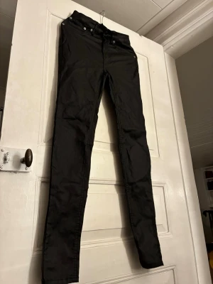 Svarta skinny jeans från 157 - Säljer ett par svarta skinny jeans från 157 med klassisk femficksdesign och dragkedja fram. Jeansen har en tight passform och är tillverkade i ett stretchigt material som sitter snyggt längs benen. Perfekta för dig som gillar en slimmad look. Skulle säga att de passar storlek S.