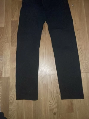 Svarta byxor från Dressmann Regular Fit - Svarta byxor från Dressmann i modellen Regular Fit. Klassisk rak passform med normal midja och diskreta sömmar. Perfekta till en stilren look och passar till många olika outfits. Materialet känns som bomull eller en bomullsblandning.