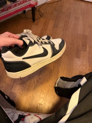 Nike Dunks - Säljer ett par Nike Dunk Low sneakers i svart och vitt skinn med klassisk swoosh på sidan. Skorna har snörning, låg profil och rund tå. Perfekta för dig som gillar streetwear och vill ha en clean look.