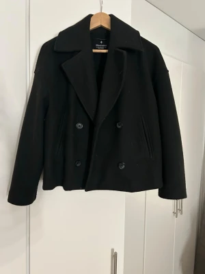 Svart kappa från Stradivarius - Säljer en svart skepparkavaj från Stradivarius i storlek XS. Jackan har knappar fram till. Lite nopprig men inte direkt något man tänker på vid användning. Perfekt nu till våren