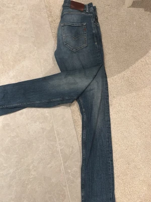 Replay MickyM blå jeans straight fit - Säljer ett par snygga Replay MickyM jeans i klassisk blå tvätt. Jeansen har raka ben, fem fickor och coola detaljer vid fickorna. Märket syns tydligt både på bakficka och insidan. Perfekta för dig som gillar en tidlös jeanslook.