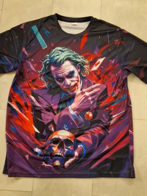 T-shirt Joker - Warner licensierad Joker grafik T-shirt. Bokstavsrund hals, 3D-tryck. Kortärmad. Polyester. T-shirt för män och kvinnor.