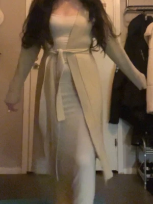 Beige ribbad cardigan jacka med bälte - Lång, ribbad cardigan jacka i beige från H&M. Jackan har ett bälte i midjan och är långärmad. Färgen i värkligheten liknar de 2 första bilder (ljustet på sista är lite mörkt) 