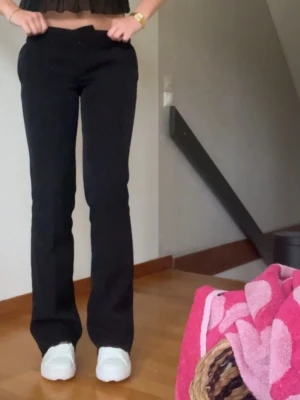 Svarta bootcut kostymbyxor - Säljer ett par svarta bootcut kostymbyxor med snygg passform och klassisk look. Byxorna har en low waist  och är tillverkade i ett mjukt material som sitter skönt hela dagen. Perfekta till sneakers eller boots för en clean stil.