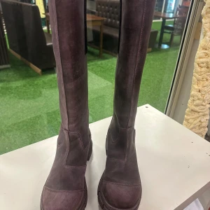 Mörkbruna höga boots från Ganni 41 - Säljer ett par chunky höga boots från Ganni 46 cm i lila,rosa och brun blandning  den ger en en unik färg.De har grov sula, rund tå och minimalistisk design utan snörning. Perfekta för dig som vill ha ett par statement boots till höst och vinter.