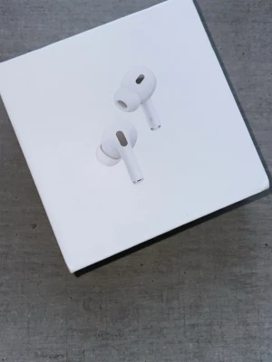 AirPods Pro 2gen - Apple AirPods Pro i originalförpackning. Trådlösa hörlurar med aktiv brusreducering och hög ljudkvalitet. Förpackningen ser ut att vara i gott skick utan synliga skador eller slitage.