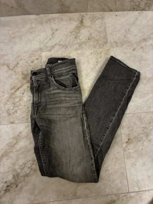 Replay svarta jeans straight fit - Säljer ett par svarta Replay jeans med snygg tvättad look och raka ben. Klassisk femficksmodell med Replay-logga på bakfickan och coola sömmar. Jeansen har normal passform och är gjorda i slitstarkt denim-material.