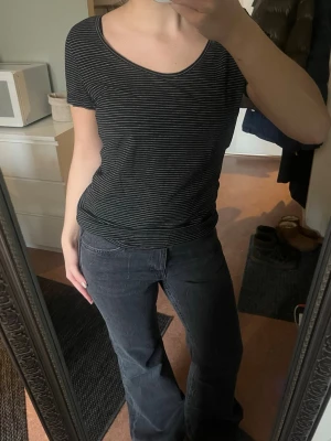 Svartvit randig t-shirt från H&M Basic - En svart t-shirt med tunna vita ränder från H&M Basic. Modellen är klassisk med rund halsringning och korta ärmar. Storlek m men passar xs/s bra!