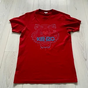Röd Kenzo t-shirt med tigertryck - Säljer en röd t-shirt från Kenzo i storlek. Perfekt för dig som gillar streetstyle och vill sticka ut. Vid intresse bara att höra av sig! 