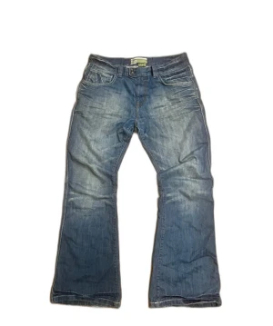 Blå jeans Moto W36 L34 bootcut  - Det är typ igenkligen w34 skulle jag säga. Snygga blå jeans från Moto med bootcut passform och coola detaljer vid bakfickorna. Jeansen har klassisk femficksdesign, dragkedja och knapp i midjan. Materialet är slitstarkt denim och färgen är mellanblå med lätt tvättad look.