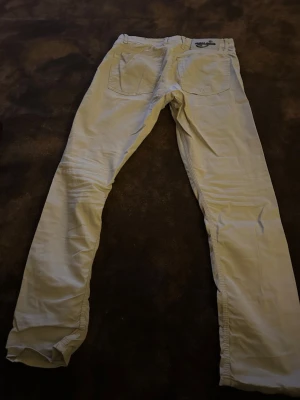 Beiga jeans från Jacob Cohen - Snygga beiga jeans från Jacob Cohen, tillverkade i Italien. Byxorna har klassisk femficksdesign, raka ben och normal passform. Materialet är bomull med en mjuk känsla och detaljer som metallmärke på bakfickan. Perfekt för dig som gillar stilrena och exklusiva jeans.