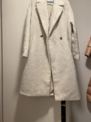 Vit pälsjacka från VILA - Säljer en fluffig vit pälsjacka från VILA med klassisk krage och dubbelknäppning framtill. Jackan har lång ärm och en oversized passform som ger en cool och trendig look. Perfekt för att hålla sig varm och snygg under kyliga dagar.