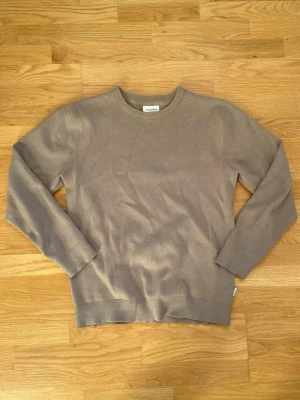 Beige stickad tröja från Lindbergh - Snygg beige stickad tröja från Lindbergh. Tröjan har rund halsringning och långa ärmar med ribbade muddar. Perfekt för dig som gillar enkel och stilren design. Materialet är mjukt och skönt mot huden.