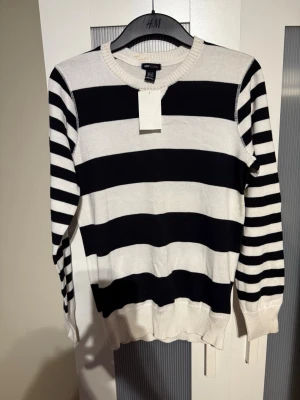 Randig svartvit tröja från H&M Young - Snygg långärmad tröja från H&M Young i storlek 170. Tröjan har breda svarta och vita ränder på kroppen och smalare ränder på ärmarna. Rund halsringning och ribbade muddar vid ärmslut och nederkant. Perfekt för dig som gillar klassisk streetstil.