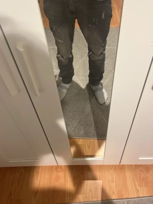 Supply and demand jeans - Säljer ett par grå jeans med coola slitningar och färgstänk för en avslappnad streetlook. Byxorna har smal passform och klassisk femficksdesign. Perfekta för dig som gillar en edgy stil.