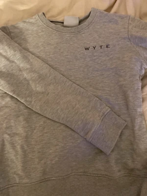 Grå sweatshirt från Wyte XS - Säljer en stilren grå sweatshirt från Wyte i storlek XS. Tröjan har rund hals, långa ärmar och diskret logga på bröstet. Mjuk och skön bomullsmix som passar perfekt till chill eller skola. Ribbstickade muddar vid ärmslut och nederkant.