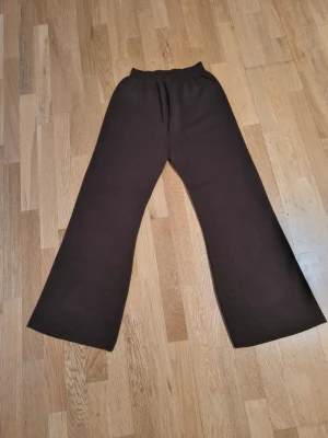 Bruna stickade wide byxor - Mörkbruna stickade byxor med breda ben och elastisk midja. Byxorna har en loose passform och är perfekta för en chill och avslappnad stil. Materialet är mjukt och ger en skön känsla mot huden. Snygga att matcha med en enkel t-shirt eller hoodie.