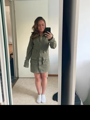 Rome Strijd x Nakd - Säljer en snygg grön jeansklänning som är använd 1 gång och tyvärr inte kommer till användning. Väldigt stretchig och går att justera i midjan. 