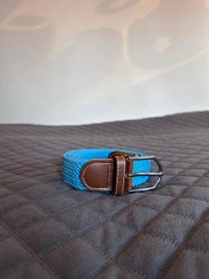 Blått flätat bälte - Tja det är helt nytt från bältgallerian i storlek 105cm långt och 3,5cm brett. Det är gjort i ett elastiskt material och man kan anpassa längden vart man än vill. Om du inte gillar den här färgen finns flera andra att välja mellan. Desto mer du köper desto billigare blir det. Säljer också armband.
