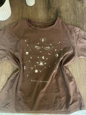 T-shirt från Lager 157 - Brun t-shirt från Lager 157 med astrologiskt tryck. Använd flertal gånger! Skulle säga att tröjan passar både en XS och S. Tar emot prisförslag!