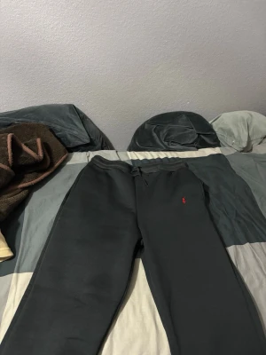 Polo mjuks byxor - Svarta mjukisbyxor från Polo Ralph Lauren med dragsko i midjan och klassisk röd logga broderad på vänster sida. Byxorna har en avslappnad passform och är tillverkade i mjukt material som är perfekt för chill dagar. Storlek xxl.