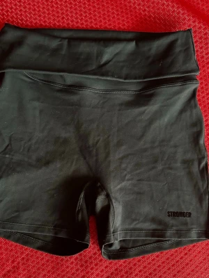 Svarta träningsshorts från Stronger S - Svarta, högmidjade träningsshorts från Stronger med bred linning och tight passform. Perfekta för gymmet eller löprundan. Materialet är stretchigt och följsamt för maximal rörelsefrihet.