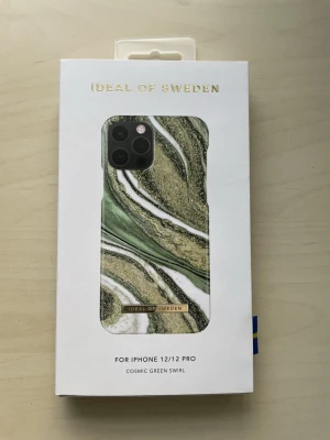 Cosmic Green Swirl skal iPhone 12/12 Pro - Snyggt mobilskal från iDeal of Sweden till iPhone 12/12 Pro i Cosmic Green Swirl-design. Skalets mönster har gröna, vita och guldiga marmorränder och är gjort i ett hårt plastmaterial. Perfekt för dig som vill ha ett trendigt och stilrent skydd till mobilen.