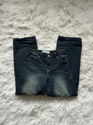 Mörkblå raka jeans från Gina Tricot - Mörkblå jeans med raka ben och klassisk femficksmodell från Gina Tricot. Jeansen har en lätt tvättad look framtill och baktill samt bälteshällor och knappgylf. Perfekta för en avslappnad stil.