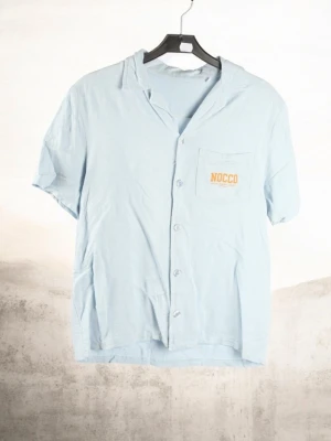 ​👕 NOCCO Short Sleeve Shirt - Sky Blue - ​👕 NOCCO Short Sleeve Shirt - Sky Blue ​Description: Fresh and lightweight short-sleeved shirt from NOCCO. Made from 100% viscose, giving it a soft feel and a great summer drape. Features a stylish camp collar and an embroidered logo on the chest pocket. Perfect for summer days or beach wear! ​Material: 100% Viscose ​Condition: Great pre-loved condition ​Style: Relaxed fit / Camp collar ​#nocco #summer #skater #viscose #streetwear #beachwear #casual #pastel #merch