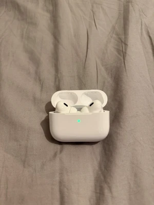 Apple AirPods Pro (2nd generation) - Säljer ett par vita Apple AirPods Pro (2nd generation) med trådlöst laddningsetui. Snygg och kompakt design med silikonproppar och aktiv brusreducering. Perfekta för musik, poddar och samtal. Levereras i originalförpackning.