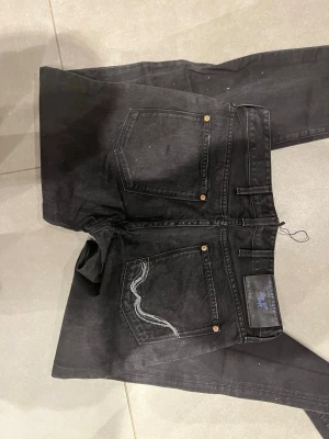 Svarta jeans från replay - Säljer ett par svarta jeans från replay med klassisk femficksmodell och kontrastsöm på bakfickan. Jeansen har raka ben och kopparfärgade nitar. Materialet är denim i bomull och de har en cool, avslappnad look.