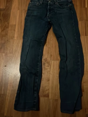 Levis 501 - Säljer ett par levis 501 jeans i klassisk modell med fem fickor och snygga sömmar baktill. Jeansen har en rak passform. Perfekta till en avslappnad stil och passar till det mesta.