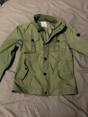 J.Lindeberg Field Jacket - Snygg Oliv grön Field Jacket från J.Lindeberg. Passar som M. Skriv vid funderingar!