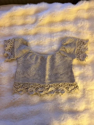 Beige virkad croppad topp - Superfin beige croppad topp med virkade detaljer och korta ärmar. Toppen har vackra spetskanter både vid ärmslut och nederkant. Perfekt att styla med höga jeans eller kjol. Storlek xs❤️