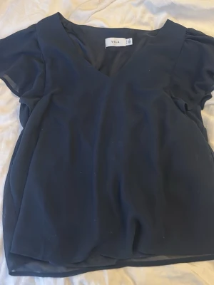 Mörkblå blus med v-ringning från Vila - Nypris var 299kr. Har aldrig använt den i och med att sverige är så pass kallt. Mörkblå blus från Vila med v-ringad hals och transparenta, korta ärmar. Perfekt att matcha med både jeans och kjol. Köpte från zalando💕