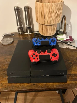 Ps4 med 2 kontroller - Säljer en PlayStation 4 (ps4) i fint skick med två DualShock 4 kontroller (en röd och en blå). Konsolen är välvårdad och fungerar utmärkt. Perfekt för spelkvällar och underhållning. Inga synliga större repor eller skador.