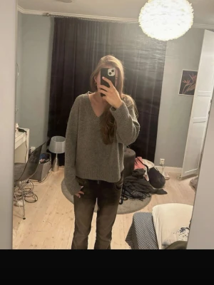 Grå oversized stickad tröja Zara  - Mysig grå stickad tröja med v-ringning och avslappnad, oversized passform. Tröjan har långa ärmar och bred ribbstickning vid ärmslut och nederkant. Perfekt för lager på lager och enkel att styla till olika outfits.