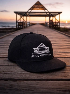 Svart keps Åhus EST.1149 - Svart keps med rak skärm och broderad vit logga framtill som föreställer en byggnad samt texten 'ÅHUS • EST.1149'. Kepsen har klassisk design med justerbar baksida. Perfekt accessoar för en stilren look. Helt ny keps och kommer från leverantör i Sverige så bra kvalitet på kepsen och själva det broderade trycket. Endast 75st i lager.