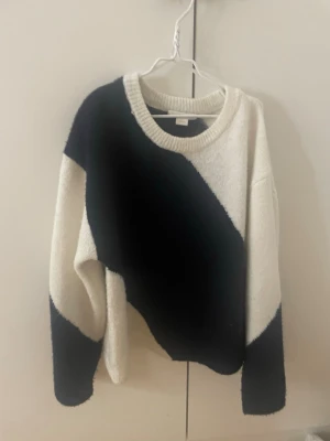 Svartvit stickad tröja Gina Tricot - Säljer en snygg stickad tröja från Gina Tricot i svart och vitt med breda diagonala blockränder. Tröjan har rund halsringning, långa ärmar och är gjord i ett mjukt, fluffigt material som känns riktigt skönt mot huden.