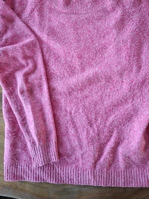 Rosa stickad tröja med rund hals - Mysig rosa stickad tröja med rund halsringning och ribbade muddar vid ärmslut och nederkant. Perfekt för lager-på-lager och enkel att matcha med jeans eller kjol. Materialet känns mjukt och fluffigt.