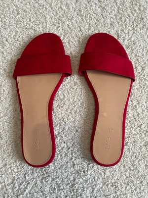 Röda sandaler från Lefties - Snygga röda sandaler från Lefties med öppen tå och stilren design. Yttermaterialet har en mjuk känsla och sulan är i beige syntetmaterial. Perfekta för dig som vill ha en färgklick till din outfit.