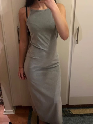 Ljusgrå långklänning i sammet - Säljer en stilren ljusgrå långklänning i mjuk sammet. Klänningen har smala axelband och en figurnära passform som ger en snygg siluett. Perfekt för dig som gillar minimalistisk och trendig stil. Aldrig haft på mig den! 