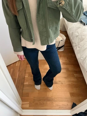 Mörkblå bootcut jeans - Snygga mörkblå bootcut jeans med klassisk femficksmodell och hög midja. Jeansen har en figurnära passform upptill och utsvängda ben nertill. Perfekta för en trendig och avslappnad look.